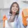 Woman smiling while cleaning window with sponge.
