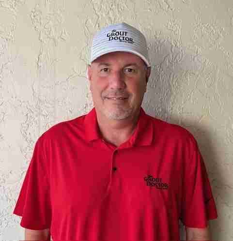 Man in red shirt and cap smiling at camera.